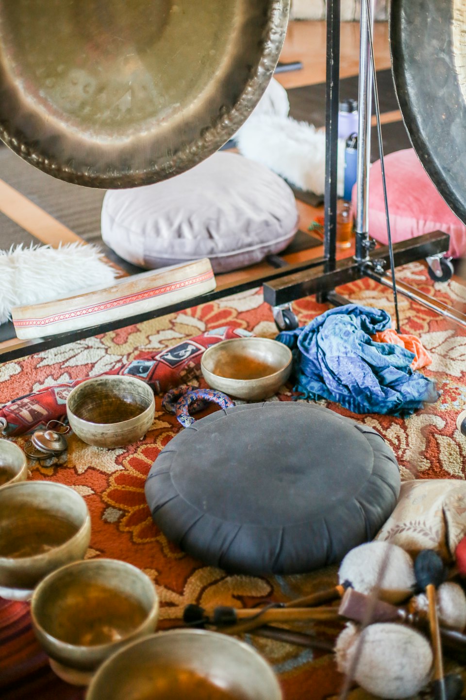 Campane tibetane e gong disposti con mazzuoli su un tappeto.