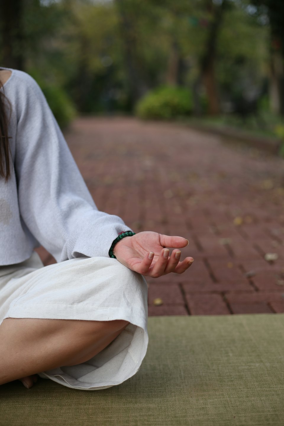 Persona che medita seduta a gambe incrociate su un tappetino da yoga.