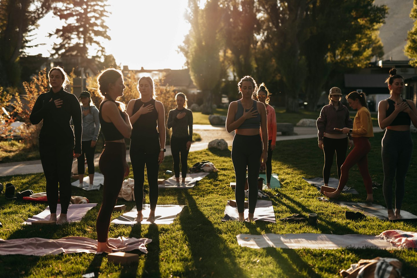 Donne che praticano yoga all'aperto su un prato soleggiato.