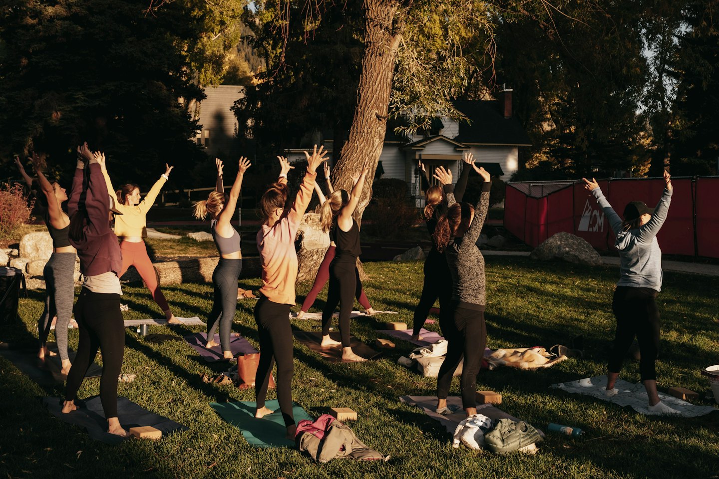 Donne che praticano yoga all'aperto al tramonto con le braccia alzate.