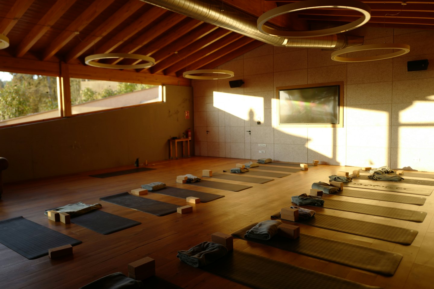Interno di uno studio di yoga moderno allestito per una lezione con tappetini e attrezzi.